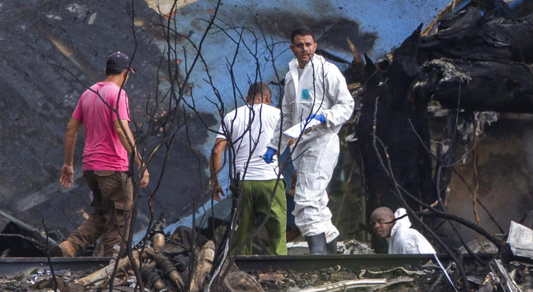 Forensic investigators and Ministry of Interior officers sift through the remains of a Boeing 737 that plummeted into a yuca field with more than 100 passengers on board, in Havana, Cuba, Friday, May 18, 2018. Cuba Plane Crash