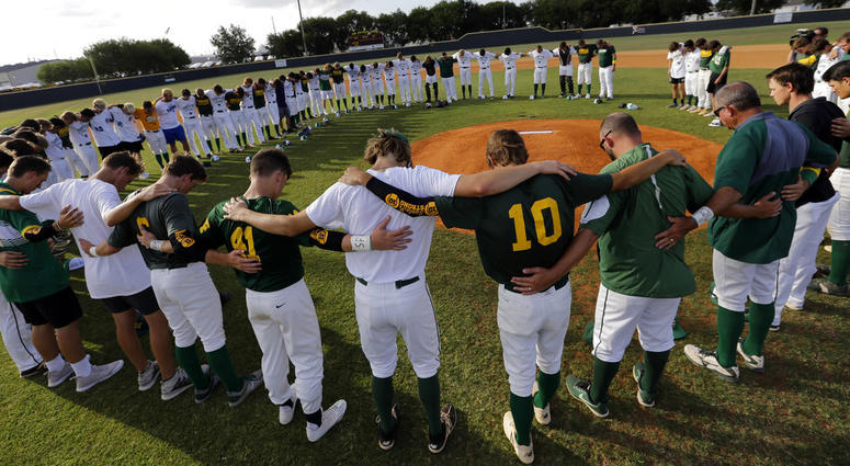 Baseball players from Santa Fe High School and Kingwood Park High School come together around the pitching mound to say a prayer before their game. Texas school shooting