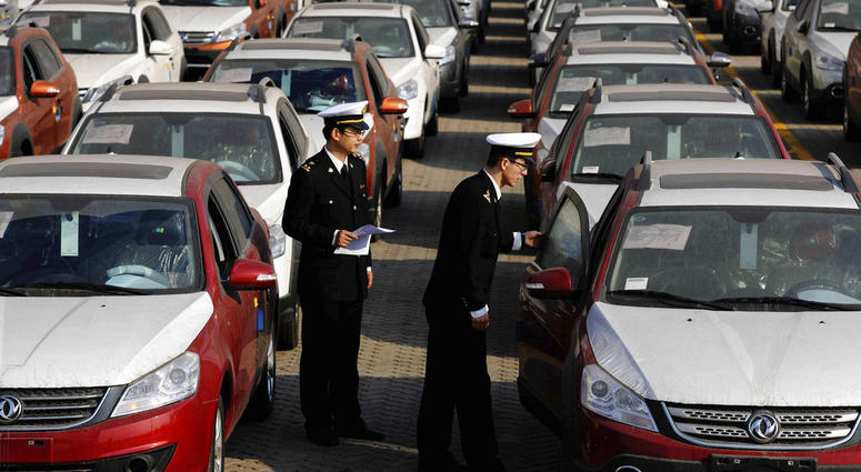 Chinese customs officials inspect cars being loaded for export at a port in Qingdao in eastern China's Shandong province. Chinese customs officials inspect cars being loaded for export at a port in Qingdao in eastern China's Shandong province.