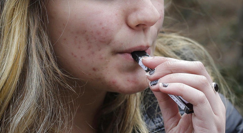 In this April 11, 2018, file photo, an unidentified 15-year-old high school student uses a vaping device near the school's campus in Cambridge, Mass. An unidentified 15-year-old high school student uses a vaping device.