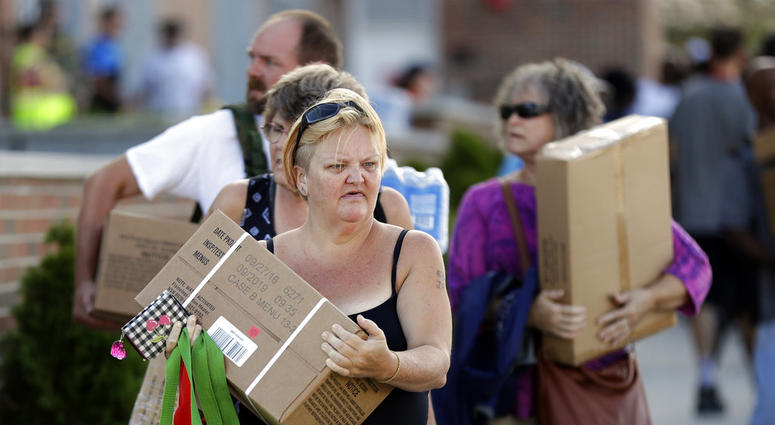 People walk away after receiving MREs, (Meals Ready To Eat) water and tarps at distribution area in Wilmington, N.C. Tuesday, Sept. 18, 2018.