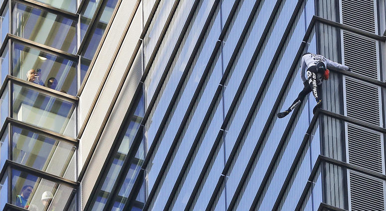 People watch from inside the building as urban climber dubbed the French Spiderman, Alain Robert scales the outside of Heron Tower building in the City of London, Thursday, Oct. 25, 2018. People watch from inside the building as urban climber dubbed the French Spiderman, Alain Robert scales the outside of Heron Tower building in the City of London, Thursday, Oct. 25, 2018.
