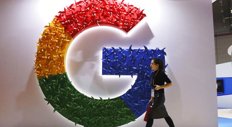 In this Monday, Nov. 5, 2018, photo, a woman carries a fire extinguisher past the logo for Google at the China International Import Expo in Shanghai. In this Monday, Nov. 5, 2018, photo, a woman carries a fire extinguisher past the logo for Google at the China International Import Expo in Shanghai.