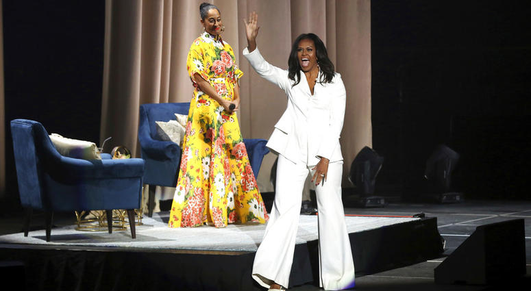 Former first lady Michelle Obama greets the audience as Tracee Ellis Ross watches at the "Becoming: An Intimate Conversation with Michelle Obama" event at the Forum on Thursday, Nov. 15, 2018, in Inglewood, Calif. Former first lady Michelle Obama greets the audience as Tracee Ellis Ross watches at the "Becoming: An Intimate Conversation with Michelle Obama" event at the Forum on Thursday, Nov. 15, 2018, in Inglewood, Calif.
