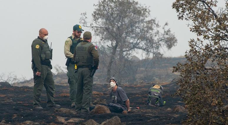 In this Thursday, Nov. 15, 2018, photo, Charlie Miles peers up at state forestry officers and state parks rangers after being arrested for trying to go home on a desolate stretch of Skyway Road between Paradise and a Chico church he was sleeping at. In this Thursday, Nov. 15, 2018, photo, Charlie Miles peers up at state forestry officers and state parks rangers after being arrested for trying to go home on a desolate stretch of Skyway Road between Paradise and a Chico church he was sleeping at.