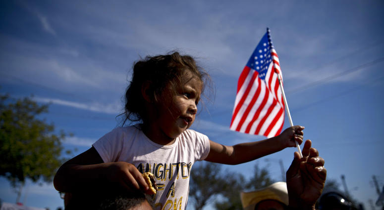 A migrant girl with a U.S. flag sits on the shoulders of a man marching with other migrants to the Chaparral border crossing in Tijuana, Mexico, Sunday, Nov. 25, 2018, as they try to reach the U.S. A migrant girl with a U.S. flag sits on the shoulders of a man marching with other migrants to the Chaparral border crossing in Tijuana, Mexico, Sunday, Nov. 25, 2018, as they try to reach the U.S.