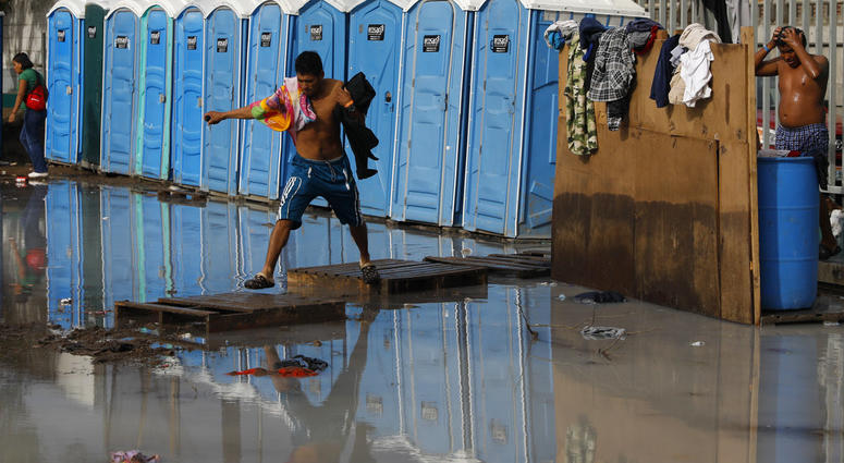 A migrant, part of the migrant caravan, try to cross a flooded area after bathing at a sports complex where more than 5,000 Central American migrants are sheltering in Tijuana, Mexico, Wednesday, Nov. 28, 2018. A migrant, part of the migrant caravan, try to cross a flooded area after bathing at a sports complex where more than 5,000 Central American migrants are sheltering in Tijuana, Mexico, Wednesday, Nov. 28, 2018.