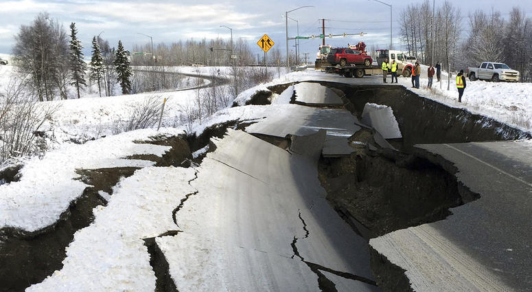 A tow truck holds a car that was pulled from on an off-ramp that collapsed during a morning earthquake on Friday, Nov. 30, 2018, in Anchorage, Alaska. Alaska Earthquake
