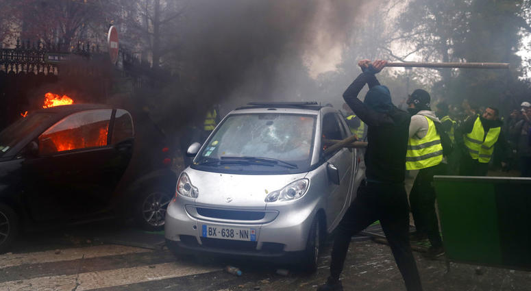Hooded demonstrators smash a car during a demonstration Saturday, Dec.1, 2018 in Paris. Hooded demonstrators smash a car during a demonstration Saturday, Dec.1, 2018 in Paris.