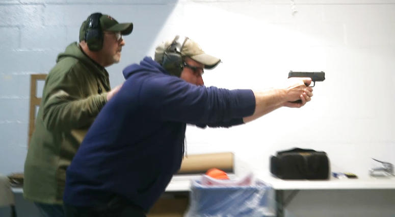 In this photo taken from a video shot on Nov. 28, 2018, Mike Carnevale places his hand on the back of Mark Hennesey while instructing him at the American Tactical Systems' indoor range in Green Island, New York. In this photo taken from a video shot on Nov. 28, 2018, Mike Carnevale places his hand on the back of Mark Hennesey while instructing him at the American Tactical Systems' indoor range in Green Island, New York.