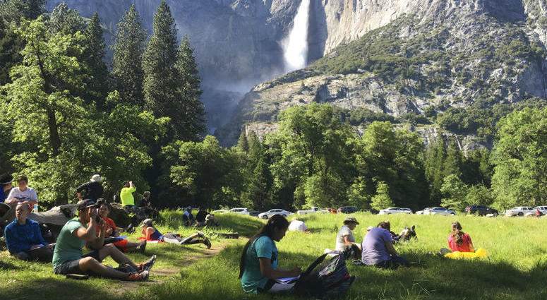 FILE - In this May 25, 2017 file photo, a class of eighth-grade students and their chaperones sit in a meadow at Yosemite National Park, Calif., below Yosemite Falls. FILE - In this May 25, 2017 file photo, a class of eighth-grade students and their chaperones sit in a meadow at Yosemite National Park, Calif., below Yosemite Falls.