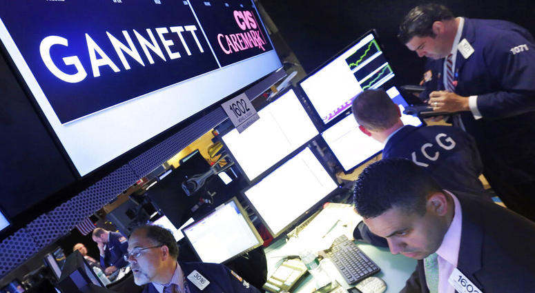 In this Aug. 5, 2014, file photo, specialist Michael Cacace, foreground right, works at the post that handles Gannett on the floor of the New York Stock Exchange. In this Aug. 5, 2014, file photo, specialist Michael Cacace, foreground right, works at the post that handles Gannett on the floor of the New York Stock Exchange.