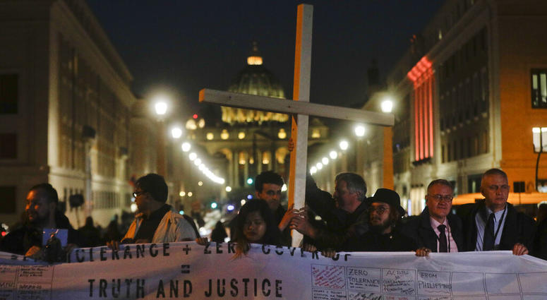 Survivors of sex abuse hold a cross as they gather in front of Via della Conciliazione, the road leading to St. Peter's Square, visible in background, during a twilight vigil prayer of the victims of sex abuse, in Rome, Thursday, Feb. 21, 2019. Survivors of sex abuse hold a cross as they gather in front of Via della Conciliazione, the road leading to St. Peter's Square, visible in background, during a twilight vigil prayer of the victims of sex abuse, in Rome, Thursday, Feb. 21, 2019.