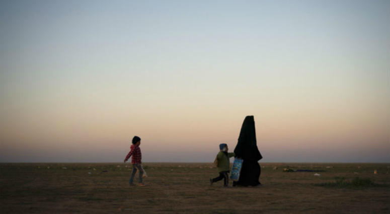 A woman walks with her children at a U.S.-backed Syrian Democratic Forces (SDF) screening area after being evacuated out of the last territory held by Islamic State militants, in the desert outside Baghouz, Syria, Friday, March 1, 2019 A woman walks with her children at a U.S.-backed Syrian Democratic Forces (SDF) screening area after being evacuated out of the last territory held by Islamic State militants, in the desert outside Baghouz, Syria, Friday, March 1, 2019