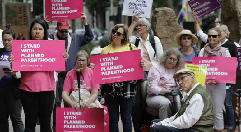 FILE - In this July 10, 2018 file photo, protesters hold signs supporting Planned Parenthood in Seattle, as they demonstrate against President Donald Trump and his choice of federal appeals Judge Brett Kavanaugh as his second nominee to the Supreme Court. FILE - In this July 10, 2018 file photo, protesters hold signs supporting Planned Parenthood in Seattle, as they demonstrate against President Donald Trump and his choice of federal appeals Judge Brett Kavanaugh as his second nominee to the Supreme Court.