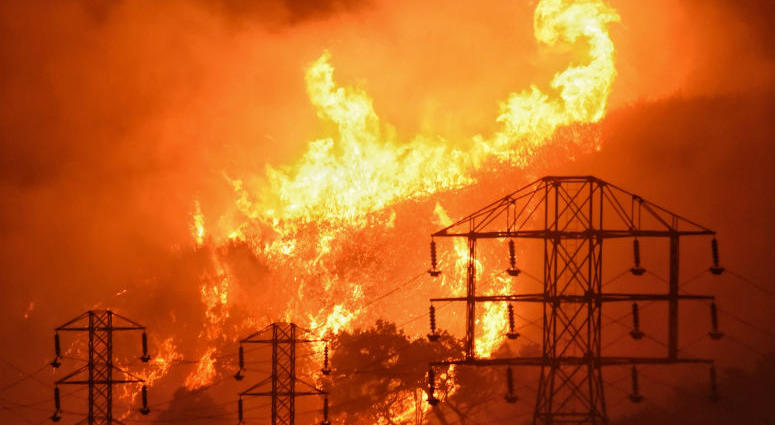FILE - In this Dec. 16, 2017, file photo provided by the Santa Barbara County Fire Department, flames burn near power lines in Sycamore Canyon near West Mountain Drive in Montecito, Calif. FILE - In this Dec. 16, 2017, file photo provided by the Santa Barbara County Fire Department, flames burn near power lines in Sycamore Canyon near West Mountain Drive in Montecito, Calif.