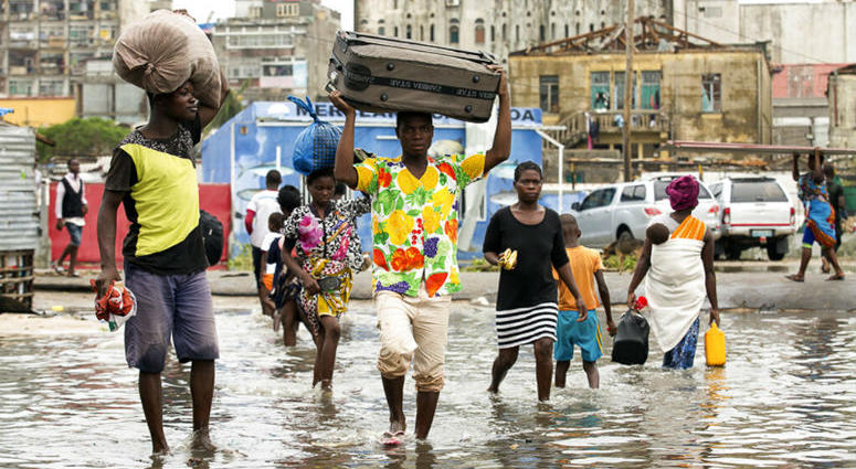 In this photo taken on Friday, March 15, 2019 and provided by the International Red Cross, people carry their personal effects after Tropical Cyclone Idai, in Beira, Mozambique. People carry their personal effects after Tropical Cyclone Idai, in Beira, Mozambique.