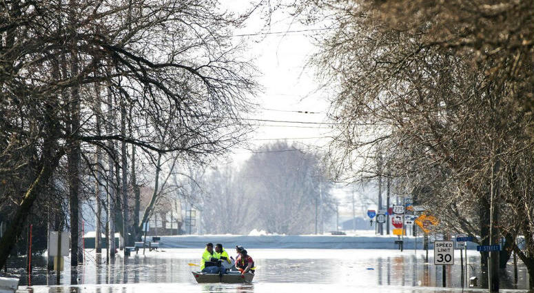 People on a boat float down floodwaters that cover Washington Street Wednesday, March 20, 2019, in Hamburg, Iowa. People on a boat float down floodwaters that cover Washington Street in Hamburg, Iowa.