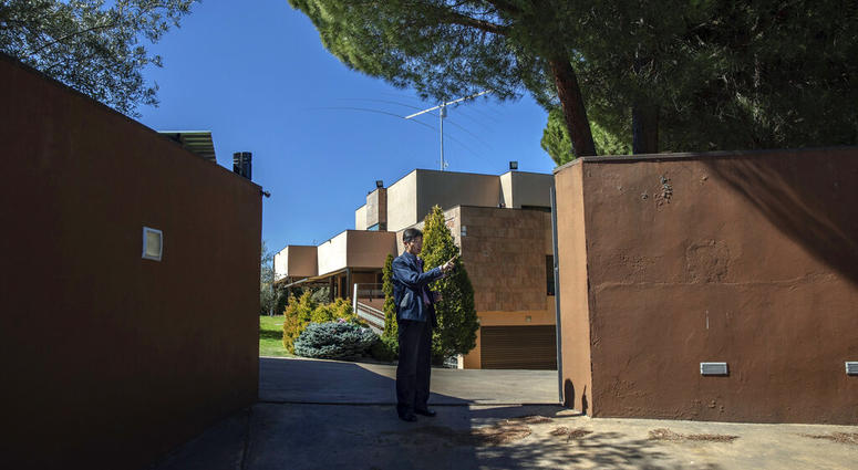 In this Wednesday, March 13, 2019 photo, a member of the North Korea's embassy tells reporters not to take pictures of the diplomatic building in Madrid, Spain. A Spanish court is accusing an American, Mexican and South Korean part of a 10-strong group that led an attack on the North Korean Embassy in February, saying the FBI was offered stolen data.