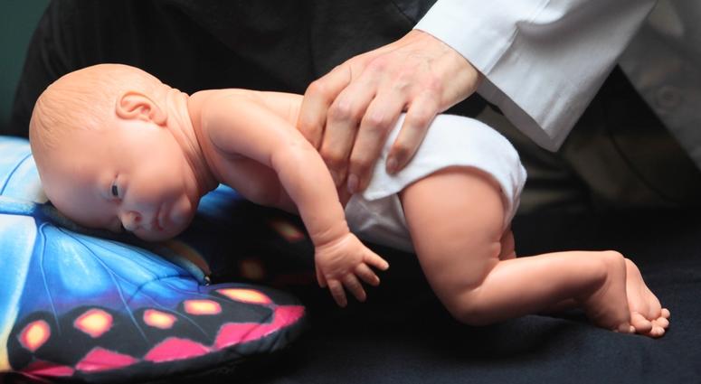 In this March 22, 2012 file photo, a doctor demonstrates how an infant can die due to unsafe sleeping practices using a scene re-enactment doll in Norfolk, Va. A doctor demonstrates how an infant can die due to unsafe sleeping practices.