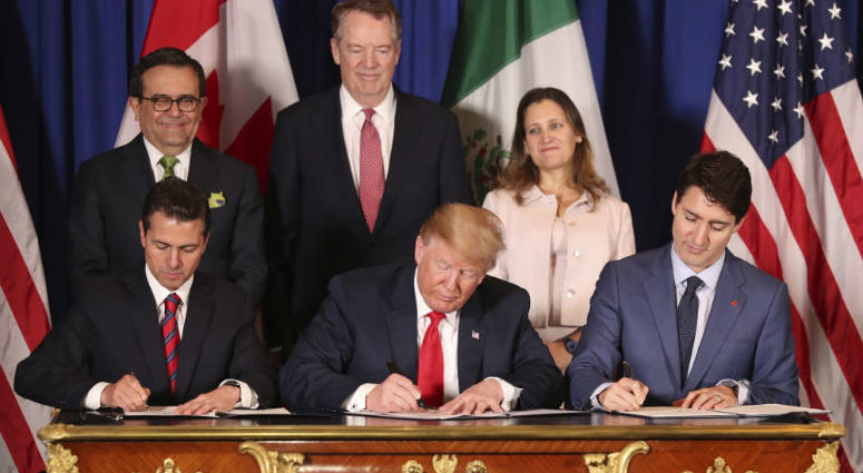 FILE - In this Nov. 30, 2018 file photo, President Donald Trump, center, sits between Canada's Prime Minister Justin Trudeau, right, and Mexico's President Enrique Pena Nieto as they sign a new United States-Mexico-Canada Agreement that is replacing the N Trump’s new North America trade agreement would give the U.S. economy only a modest boost, an independent federal agency finds.