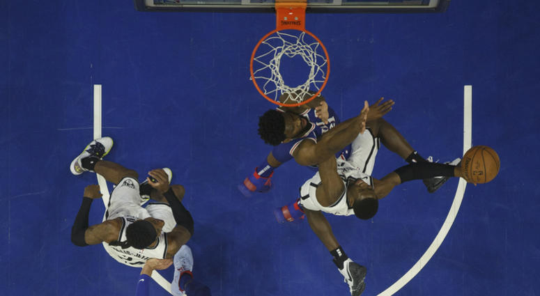 Brooklyn Nets' Caris LeVert, right, goes up for the shot against Philadelphia 76ers' Joel Embiid, center right, of Cameroon, during the first half in Game 5 of a first-round NBA basketball playoff series, Tuesday, April 23, 2019, in Philadelphia. Brooklyn Nets against Philadelphia 76ers