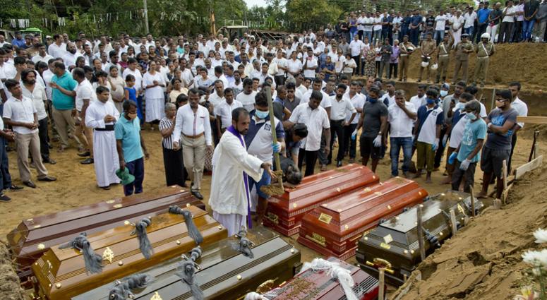 A priest conducts religious rituals during a mass burial for Easter Sunday bomb blast victims in Negombo, Sri Lanka, Wednesday, April 24, 2019. A mass burial for victims in Sri Lanka.