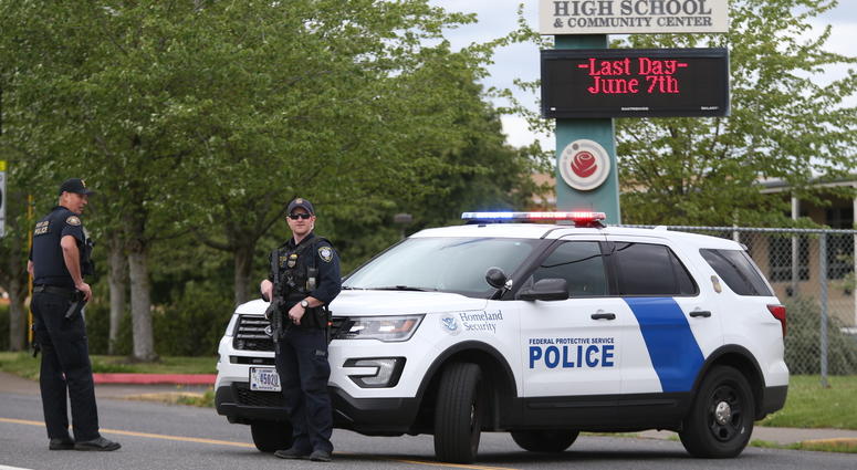 Police are positioned outside Parkrose High School during a lockdown after a man armed with a gun was wrestled to the ground by a staff member, Friday, May 17, 2019 in Portland, Ore. Police outside Parkrose High School
