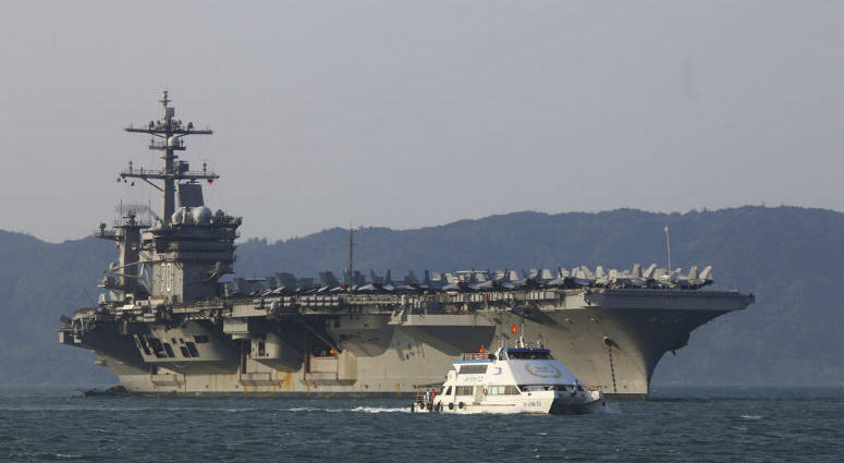 FILE - In this March 5, 2018, file photo, a Vietnamese passenger boat sails past U.S. aircraft carrier USS Carl Vinson as it docks in Danang bay, Vietnam. A U.S. sailor has pleaded guilty to espionage and sentenced to three years after admitting he took classified information about a Navy's nuclear-powered warship and planned to give it to a journalist and then defect to Russia officials said Friday, May 24