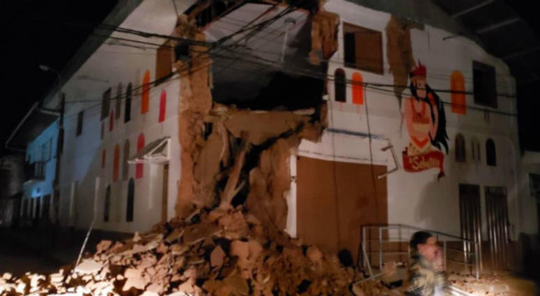 In this photo provided by Firefighters of Peru, people pass in front destroyed wall in Yurimaguas Peru, Sunday, May 26, 2019. A powerful magnitude 8.0 earthquake struck the Amazon jungle in north-central Peru early Sunday.