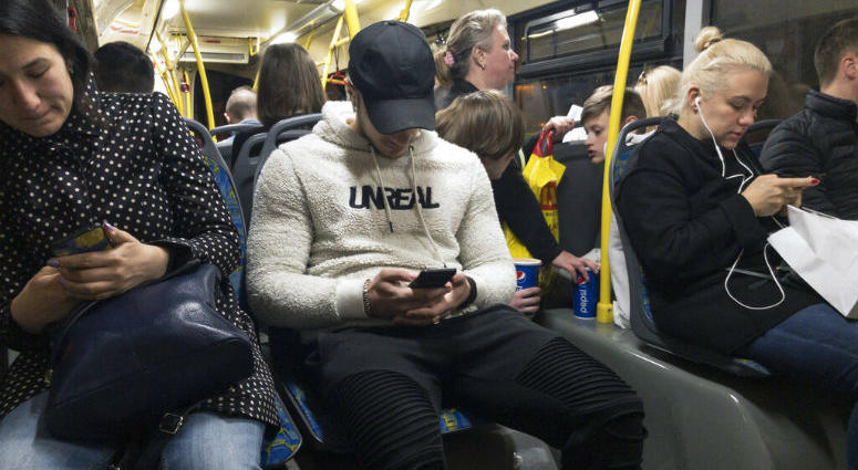 In this photo taken on Thursday, May 16, 2019, passengers look at their smartphones as they ride a bus in Moscow, Russia. Russia's communications regulator says that Tinder is now required to provide user data to Russian intelligence agencies.