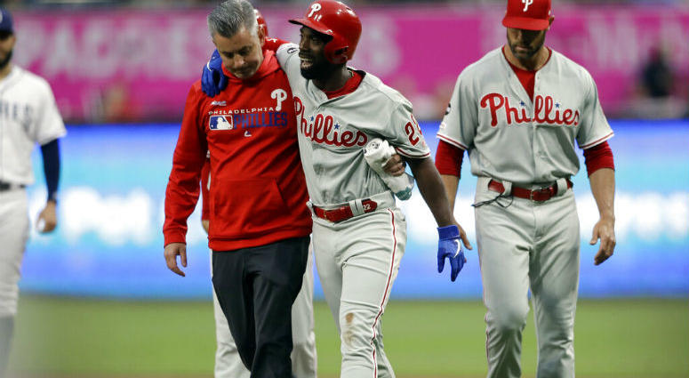 Philadelphia Phillies' Andrew McCutchen, center, is helped by a trainer after being injured while trying to get back to first base during the first inning of a baseball game against the San Diego Padres Monday, June 3, 2019, in San Diego. Philadelphia Phillies' Andrew McCutchen, center, is helped by a trainer after being injured while trying to get back to first base during the first inning of a baseball game against the San Diego Padres Monday, June 3, 2019, in San Diego.