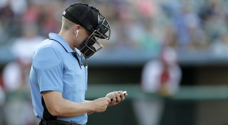 Home plate umpire Brian deBrauwere checks an iPhone while wearing an earpiece prior to the start of the Atlantic League All-Star minor league baseball game, Wednesday, July 10, 2019, in York, Pa. Umpire