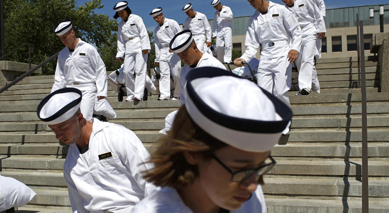 In this June 27, 2019, file photo, incoming plebes carry their belongings down a staircase during Induction Day at the U.S. Naval Academy, in Annapolis, Md. Induction Day