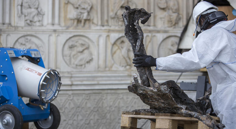 A worker cleans debris, during preliminary work to repair the fire damage at the Notre Dame de Paris Cathedral, in Paris, France, Wednesday, July 24, 2019. Notre Dame