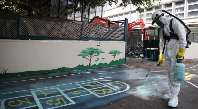 A worker sprays an adhesive product on the ground to gather up the lead particles in the school yard of Saint Benoit primary school in Paris, France, Thursday, Aug. 8, 2019. A worker sprays an adhesive product on the ground to gather up the lead particles in the school yard of Saint Benoit primary school in Paris, France, Thursday, Aug. 8, 2019.