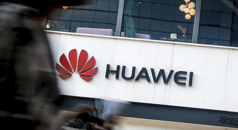 In this July 30, 2019, file photo a woman walks by a Huawei retail store in Beijing. Huawei