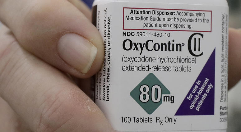 In this April 2, 2018, file photo, a pharmacist in San Francisco poses for photos holding a bottle of OxyContin. OxyContin