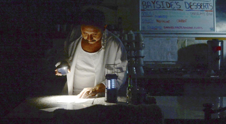Carlos Lama of Bayside Cafe, which was among businesses to lose power due to PG&E's public safety power shutoff, uses an LED lamp and light from his phone at the counter of the restaurant in Sausalito, Calif. Carlos Lama of Bayside Cafe, which was among businesses to lose power due to PG&E's public safety power shutoff, uses an LED lamp and light from his phone at the counter of the restaurant in Sausalito, Calif.