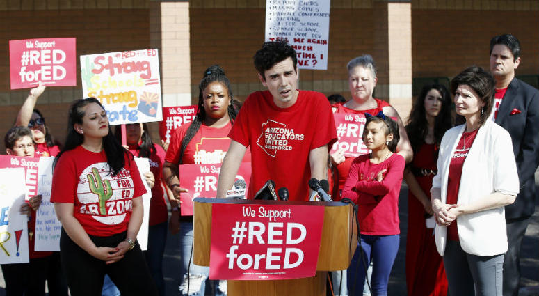 Music teacher Noah Karvelis, center, who helped organize Arizona Educators United, speaks at a news conference at the Esperanza Elementary School in Isaac School District. Music teacher Noah Karvelis