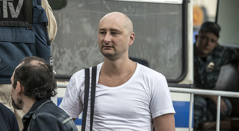 In this photo taken on Friday, May 31, 2013, Arkady Babchenko, 41, who had been scathingly critical of the Kremlin in recent years, stands at a police bus during an opposition rally in Moscow, Russia. Arkady Babchenko