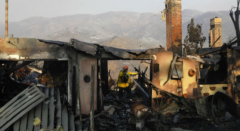 A firefighter hoses down hot spots on a wildfire-ravaged home Saturday, Nov. 10, 2018, in Malibu, Calif.