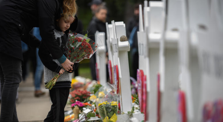 A mother and child place flowers at a memorial for victims of the mass shooting that killed 11 people and wounded 6 at the Tree Of Life Synagogue. Pittsburgh Shooting