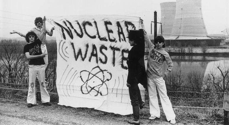 Four anti-nuclear power protesters stand holding a banner reading "nuclear waste" on Three Mile Island near Harrisburg, 1979. Three Mile Island