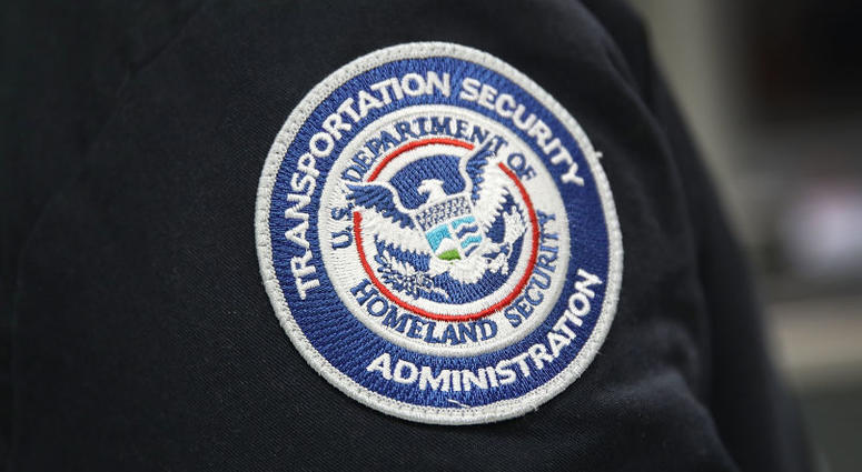 A patch is seen on the jacket of a Transportation Security Administration official as he works at the automated screening lanes funded by American Airlines. TSA