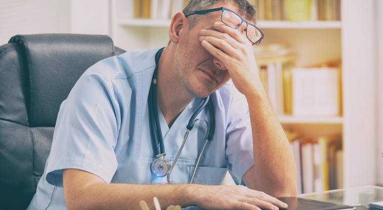 Overworked doctor in his office - stock photo Overworked doctor in his office - stock photo