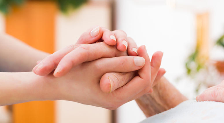 A caregiver holding a person's hand. A caregiver holding a person's hand.