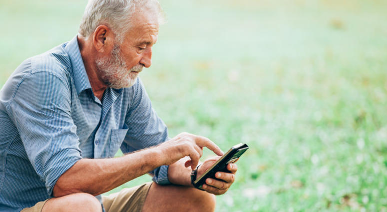 Senior men using a smartphone while sitting on grass in the park Smart Phone