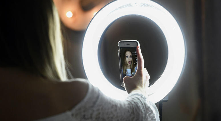 In this Feb. 28, 2018 photo, Matty Nev Luby holds up her phone in front of a ring light she uses to lip-sync with the smartphone app Musical.ly, in Wethersfield, Conn. In this Feb. 28, 2018 photo, Matty Nev Luby holds up her phone in front of a ring light she uses to lip-sync with the smartphone app Musical.ly, in Wethersfield, Conn.