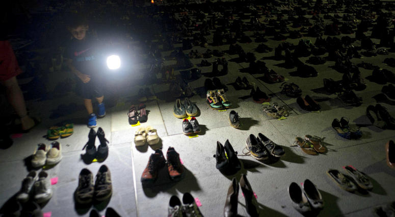 In this June 1, 2018 file photo, a child shines a light on hundreds of shoes at a memorial for those killed by Hurricane Maria, in front of the Puerto Rico Capitol in San Juan. In this June 1, 2018 file photo, a child shines a light on hundreds of shoes at a memorial for those killed by Hurricane Maria, in front of the Puerto Rico Capitol in San Juan.